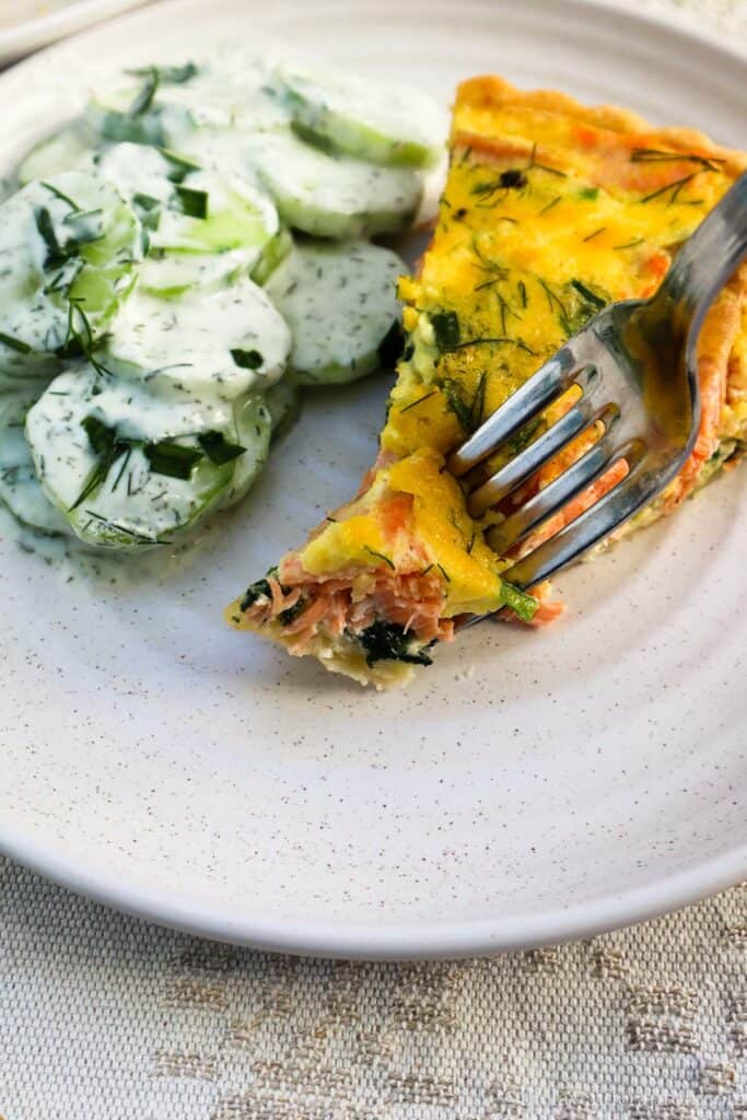 Forkful of salmon and spinach quiche with cucumber salad.