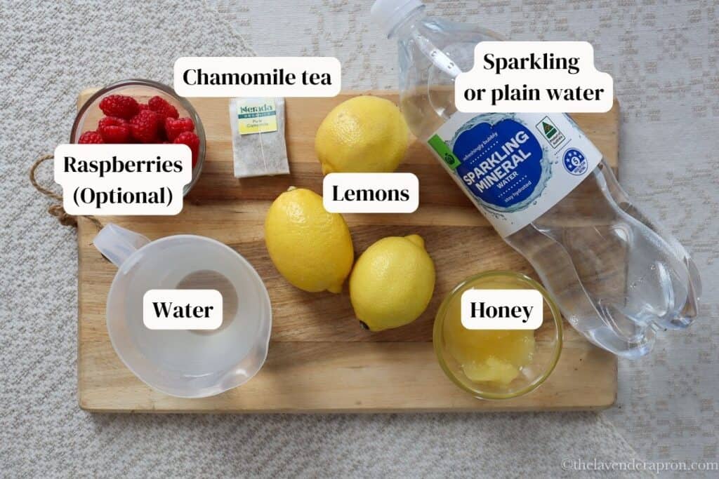 Lemons, honey, sparkling water, plain water, chamomile tea bag and raspberries, all ingredients to make lemonade.