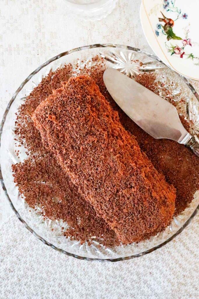 Chocolate chestnut yule log sprinkled with chocolate shavings served on a crystal serving dish.
