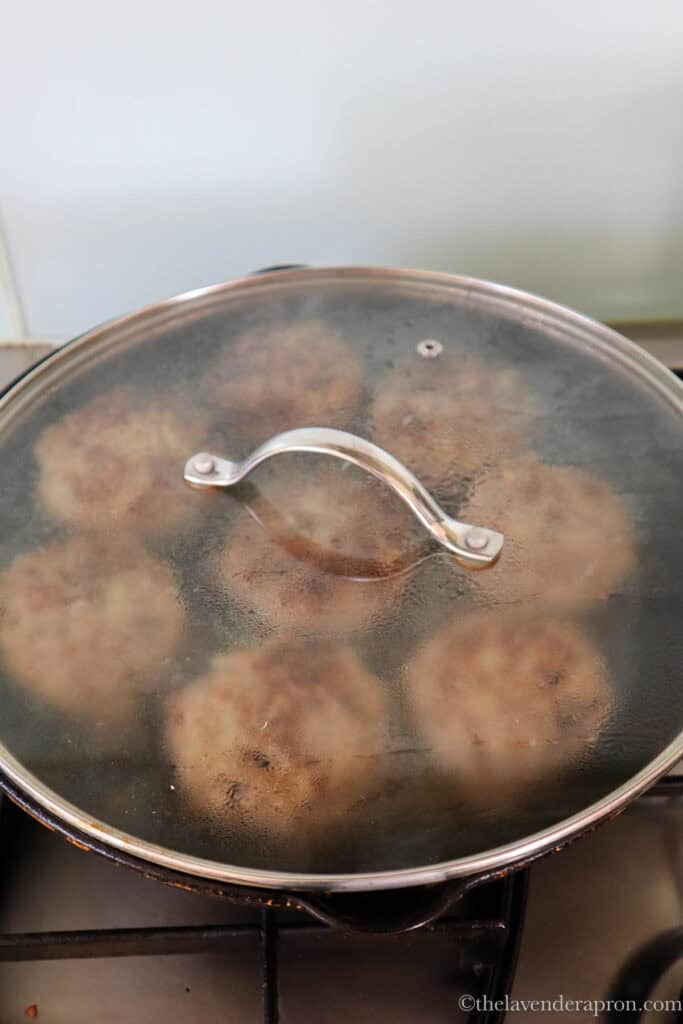 Cooking the kotletes on the pan covered with a lid.