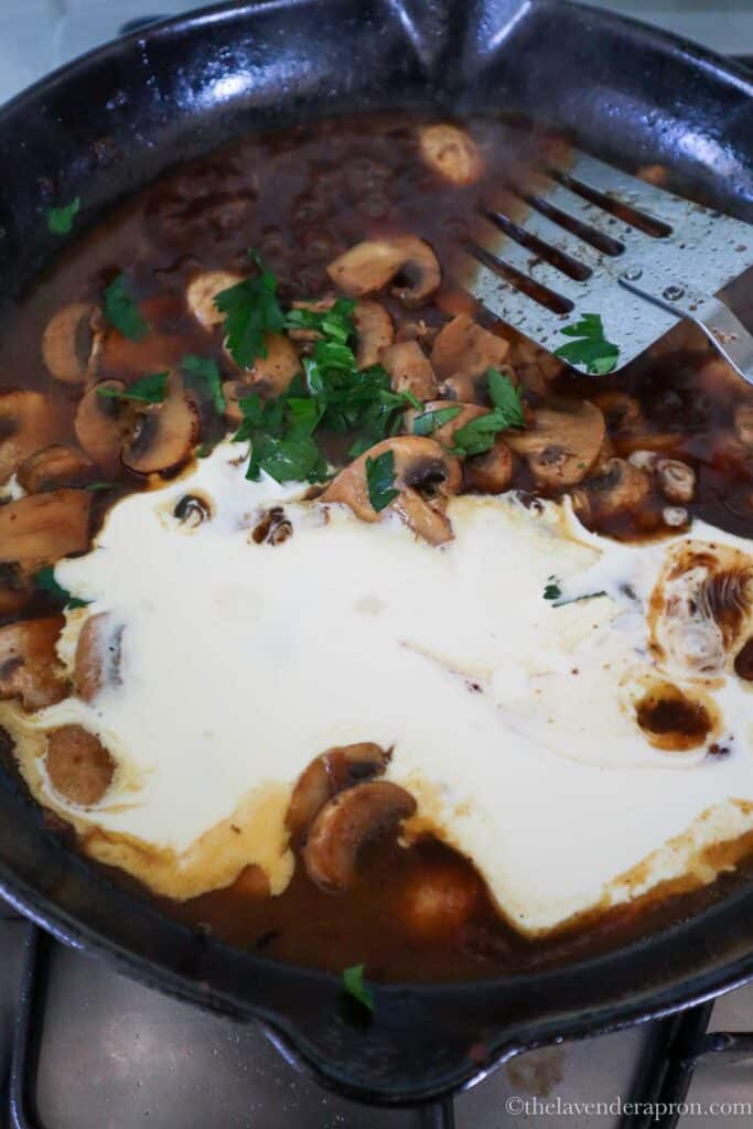 Adding cream and parsley to the sautéed mushroom mixture.