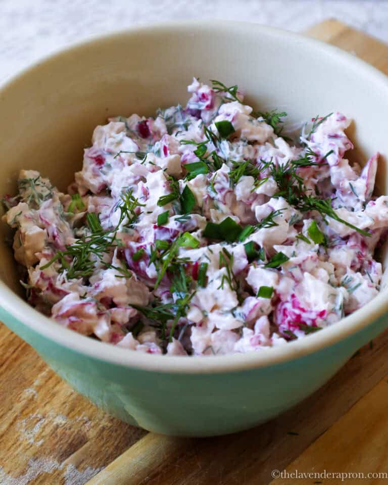 Latvian red radish salad in a green bowl with fresh dill.
