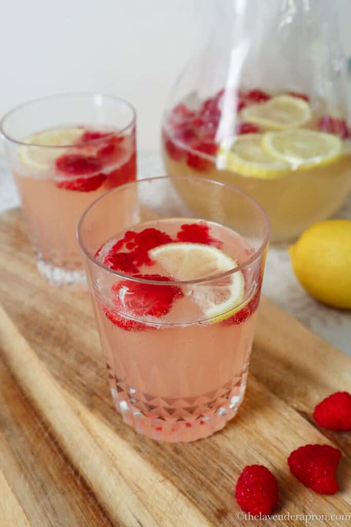 Raspberries added to jug and a glass of chamomile honey lemonade to give a slight pink color.