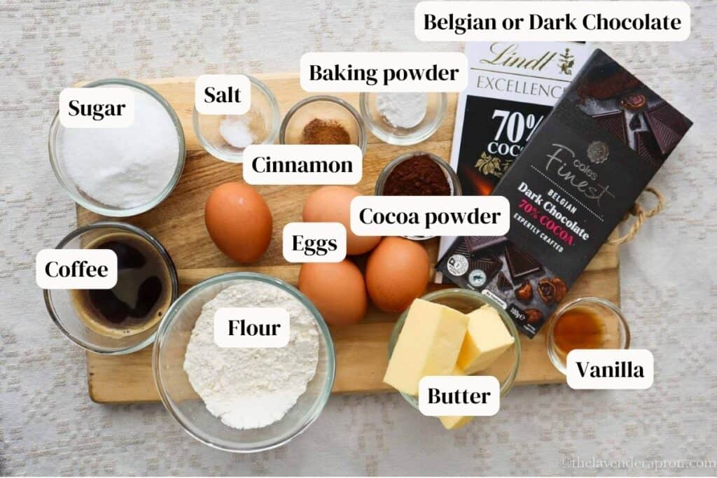 Belgian chocolate, butter, sugar, vanilla, flour, cocoa powder, baking soda, eggs, cinnamon and coffee on wooden board, which are the ingredients for Belgian chocolate cake.