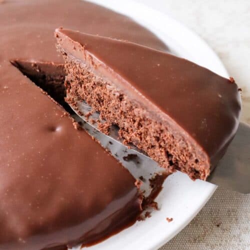 Slice of Belgian chocolate cake cut out of cake covered with chocolate ganache.