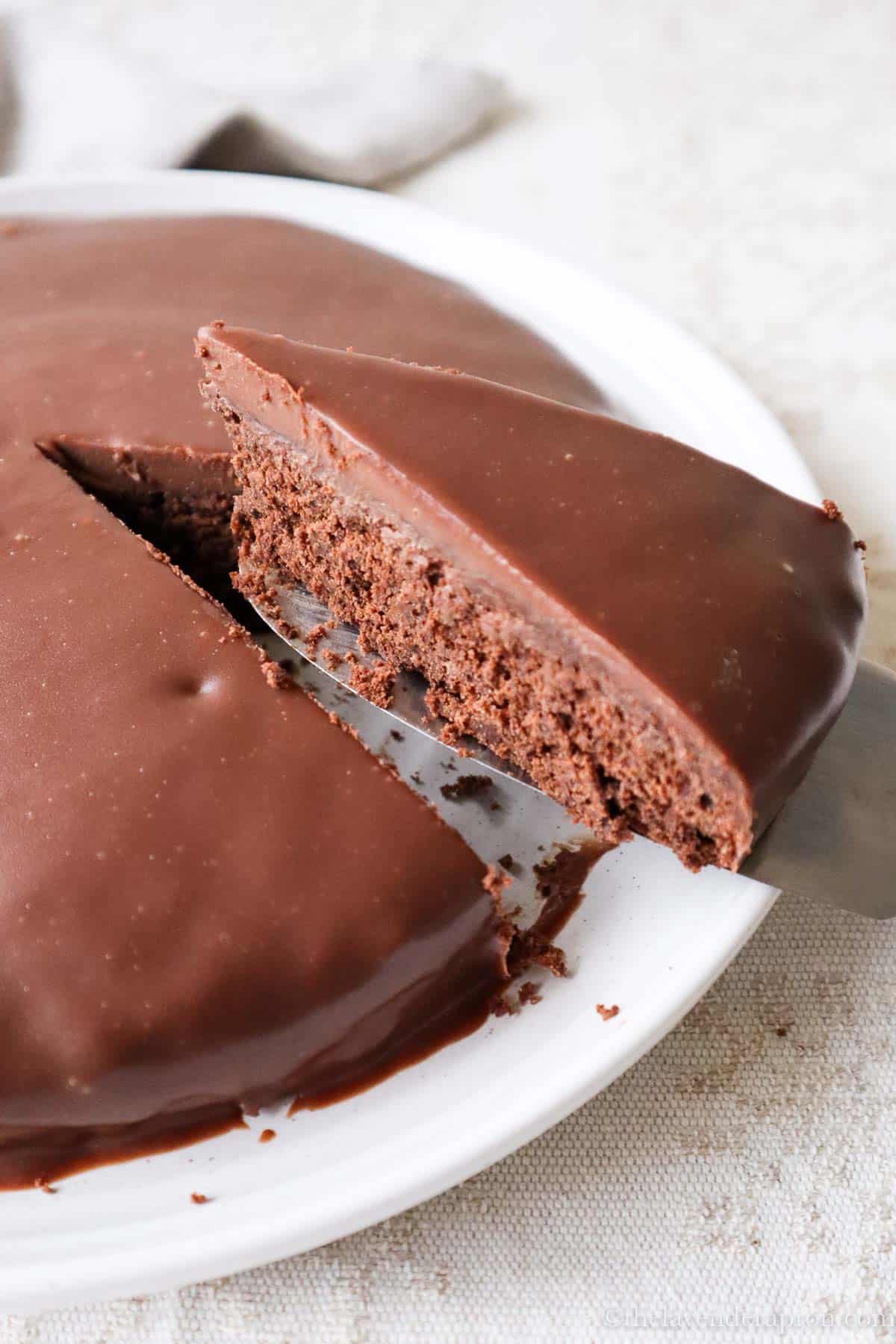 Slice of Belgian chocolate cake cut out of cake covered with chocolate ganache.