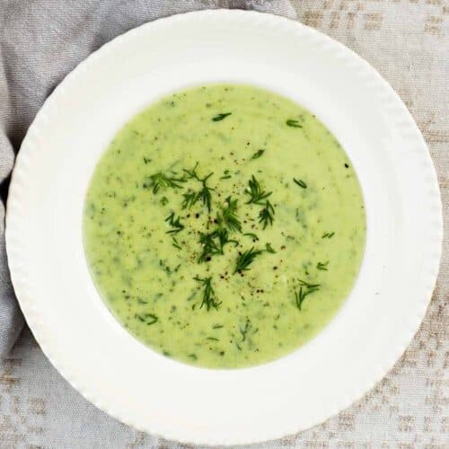 Creamy zucchini dill soup served in a beige bowl.