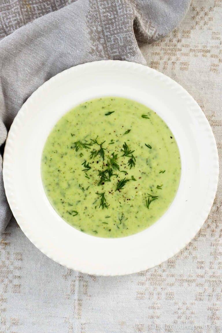 Creamy zucchini dill soup served in a beige bowl.