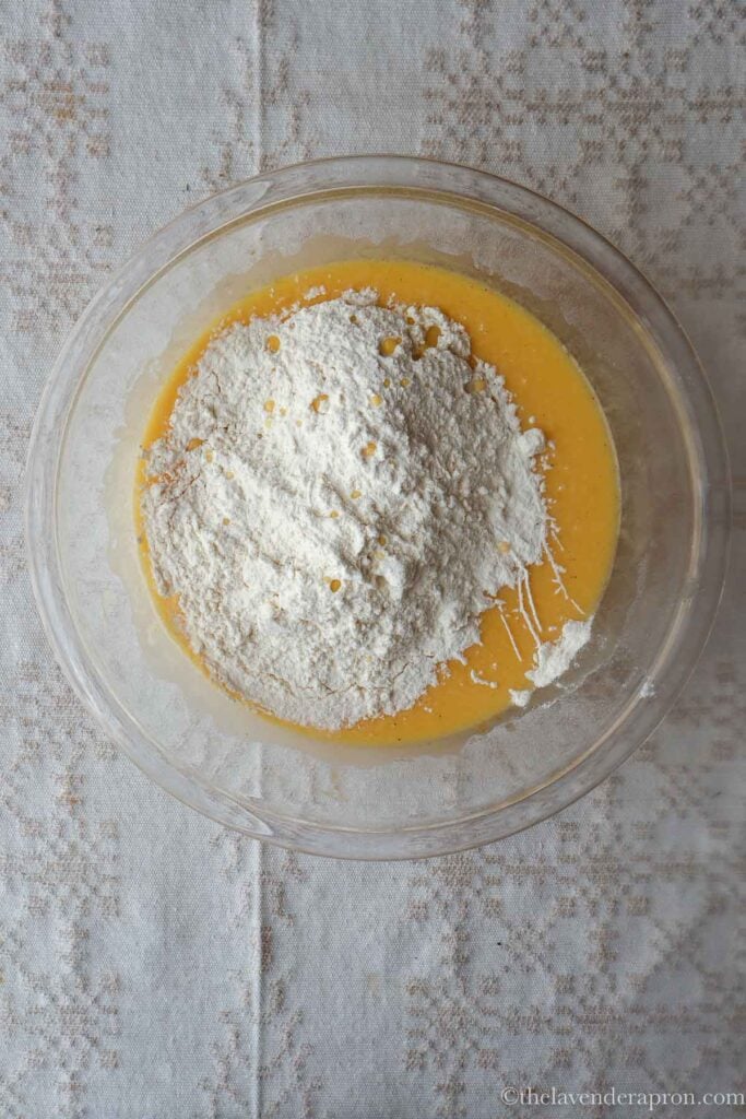 Adding sifted flour, baking powder and salt in yogurt cake mixture.