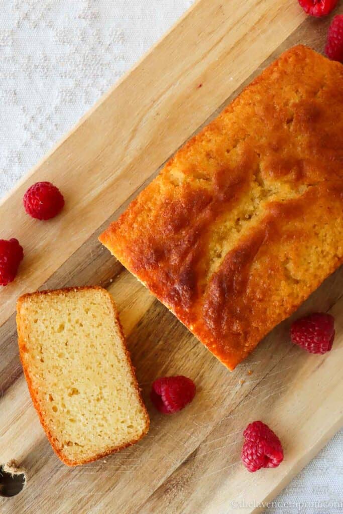 Cooled French yogurt loaf on a wooden board with one piece sliced.