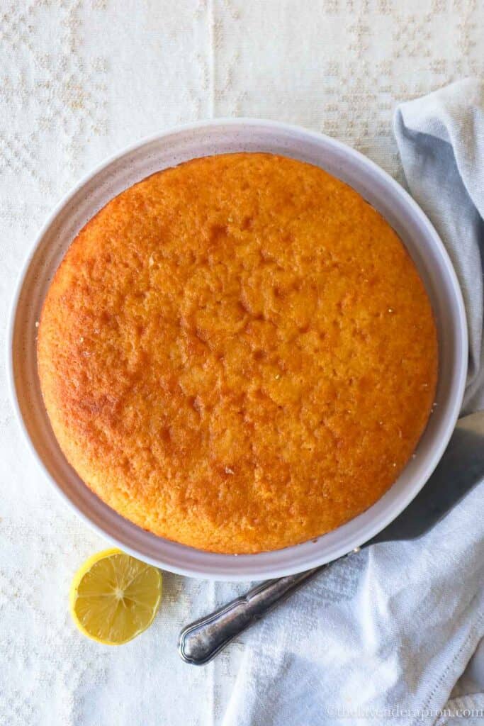 French lemon yogurt cake round form on a beige plate.