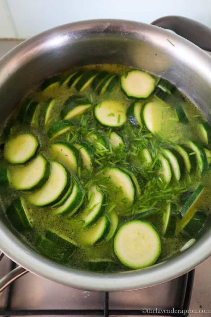 Sliced zucchini, onion, garlic and dill stems in large pot with water.
