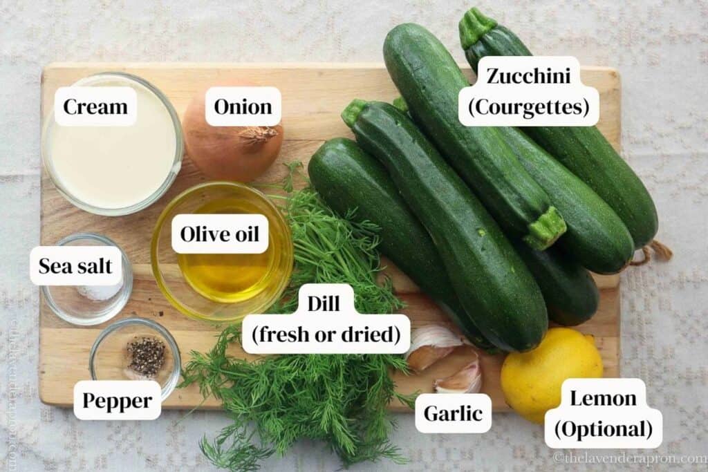Zucchini (courgettes), fresh dill, olive oil, lemon, onion on a wooden board.