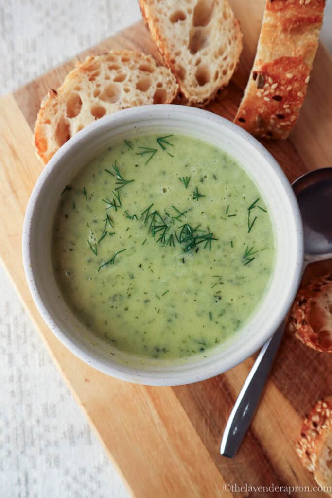 Zucchini dill soup without cream in bowl served with crusty bread.