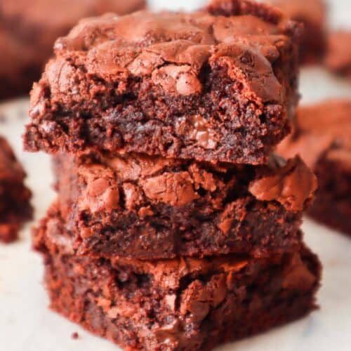 Three chocolate brownies made without cocoa powder stacked on top of another.