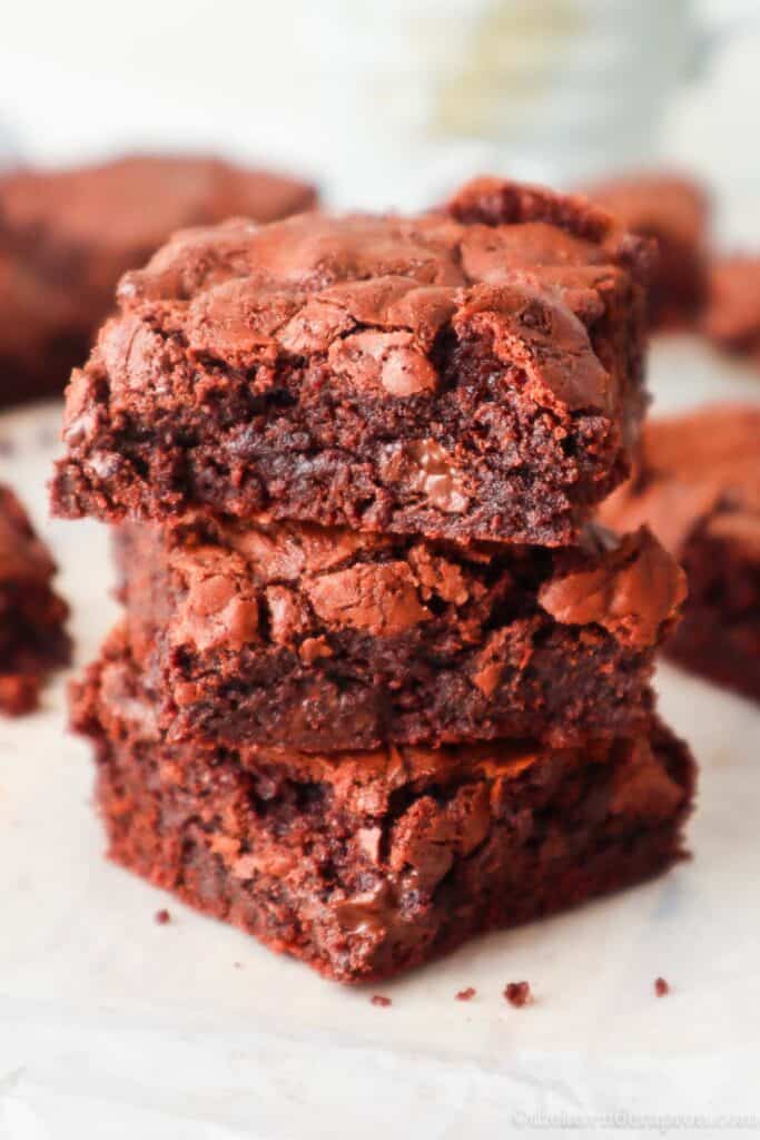 Three chocolate brownies made without cocoa powder stacked on top of another.