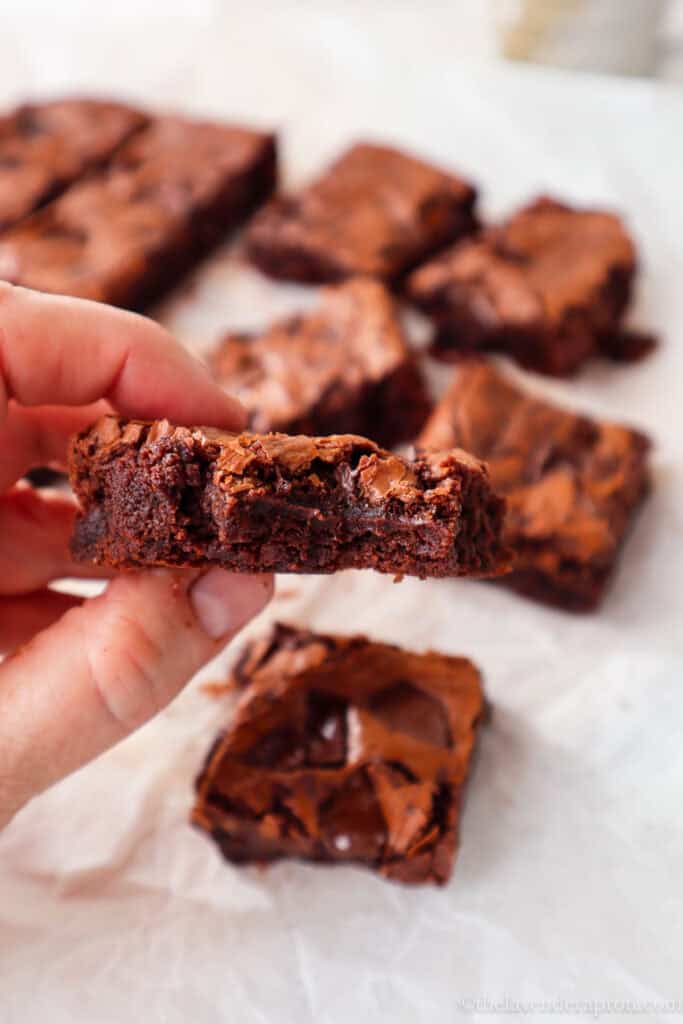 Hand holding a brownie square showing the inside moist view.