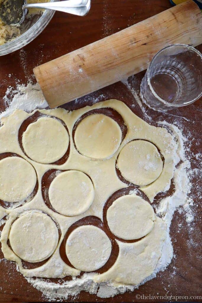 Rolling out dough and cutting circles with a drinking glass.