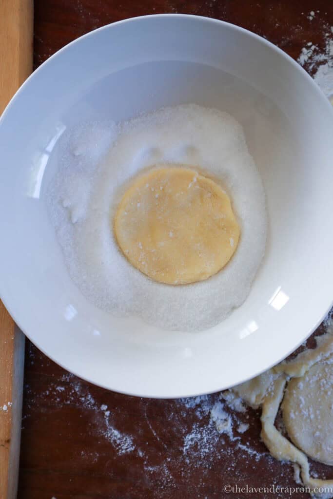 Dipping a dough circle into sugar before folding.
