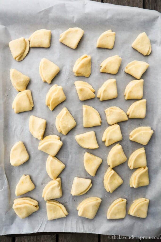 Latvian cottage cheese cookies shaped in quarter circles on a baking sheet.