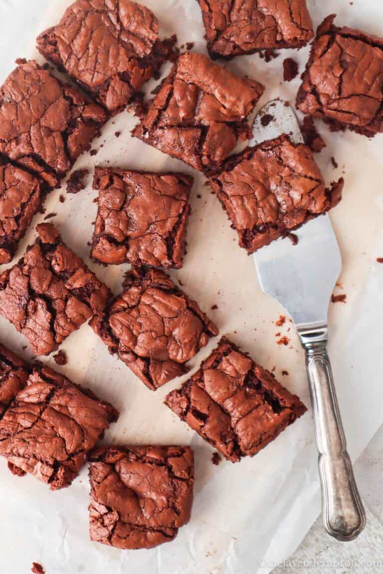 Fudgy chocolate brownies made without cocoa powder cut into squares on a parchment paper.