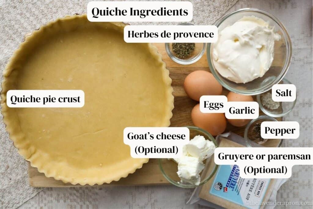 Quiche pie crust, eggs, creme fraiche, goat's cheese and gruyere cheese on wooden board.
