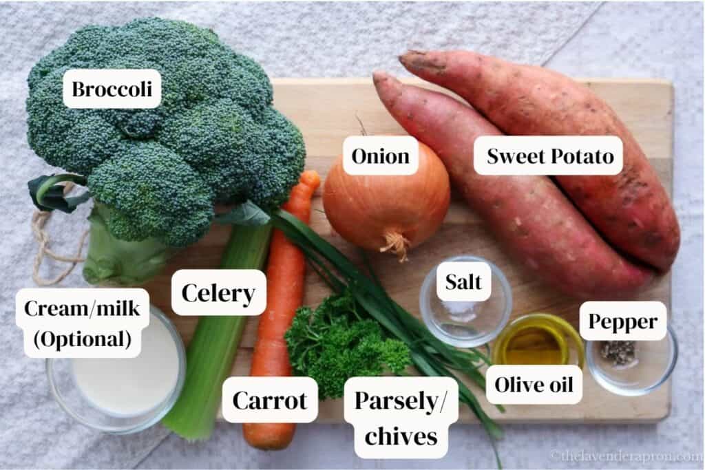 Broccoli, sweet potato, onion, carrot, celery, cream, parsley, chives, salt, olive oil and pepper on a wooden board.
