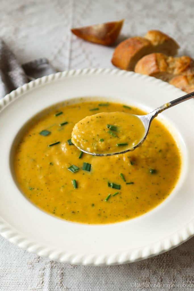 Creamy broccoli and sweet potato soup in a bowl with a spoon.