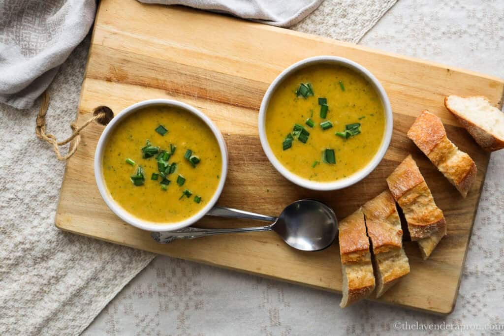 Two bowls of broccoli and sweet potato soup served with crusty bread.