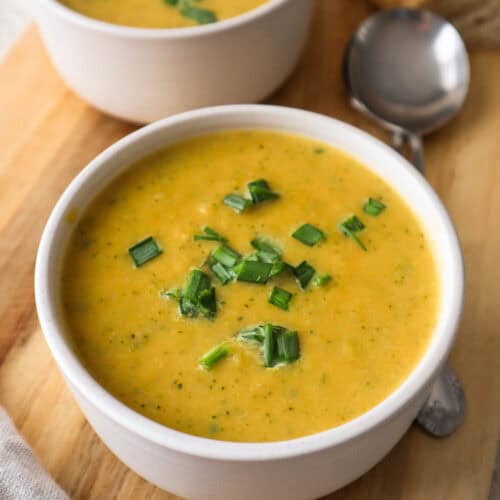 Broccoli and sweet potato soup in bowl on a wooden board.
