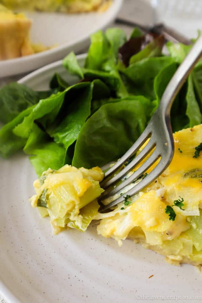 Forkful of leek and Gruyère tart served with simple lettuce salad.