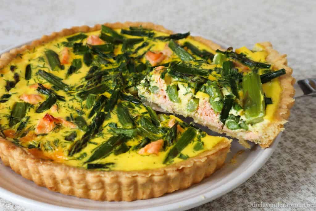 large quiche with asparagus and salmon filled slice removed.