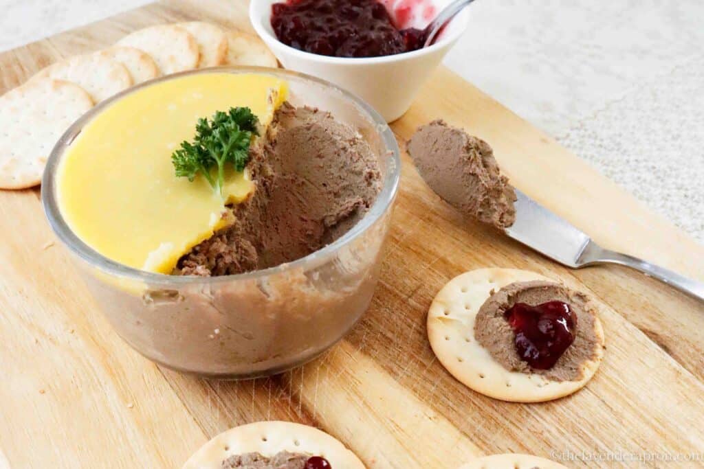 Mild chicken liver pate on a cutting board with crackers and a knife.