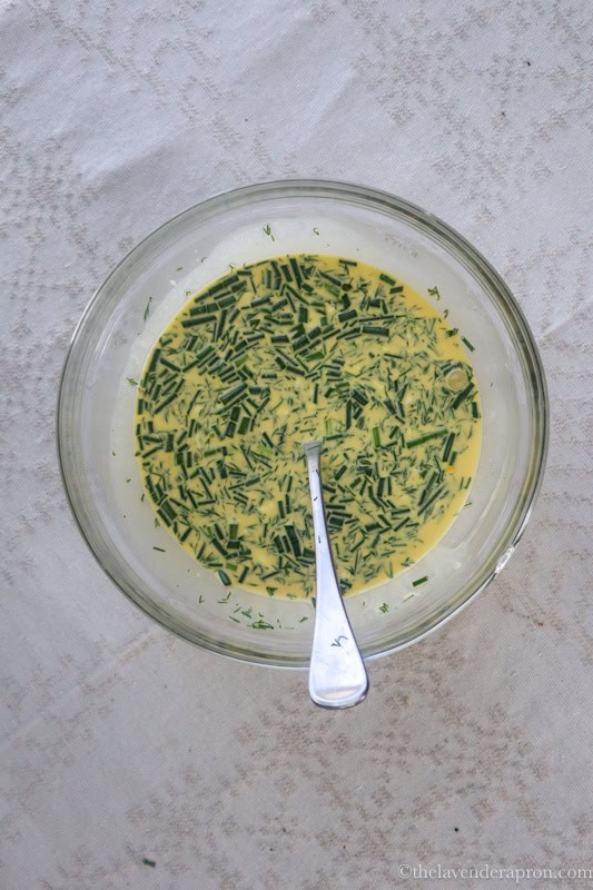 Mixing in the herbs, salt and pepper in the custard.