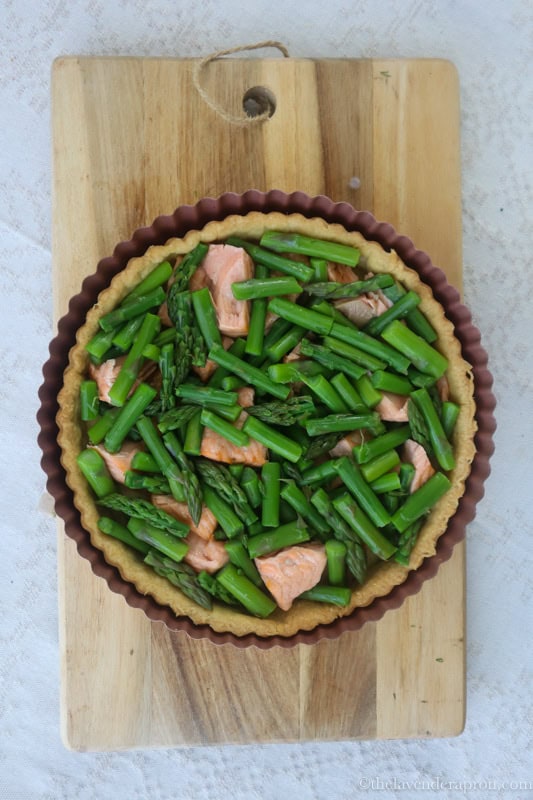 Placing the salmon and asparagus in the pie crust.