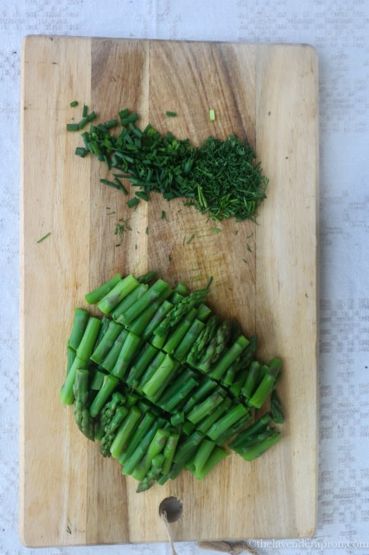 Preparing the blanched asparagus and chopping the herbs.