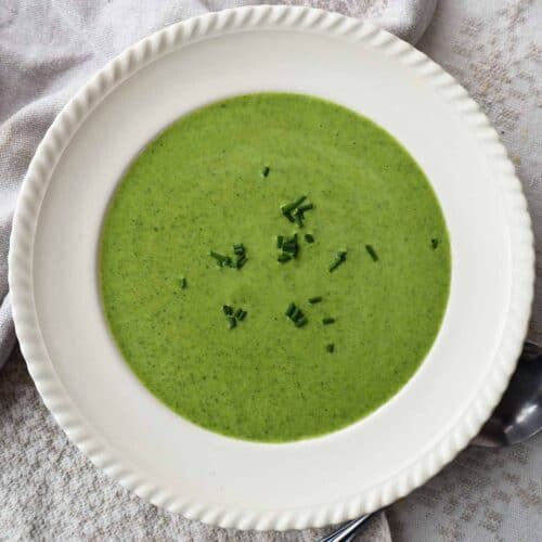 Creamy spinach leek soup in a bowl with chives as a garnish.