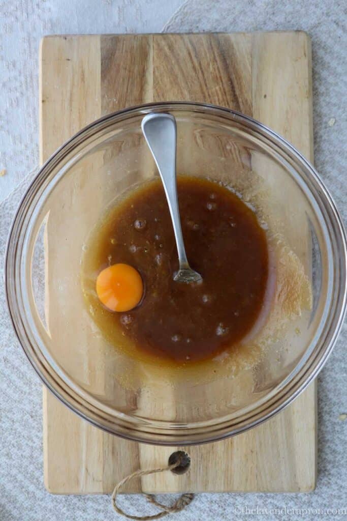 Adding in an egg to the melted butter and sugars.