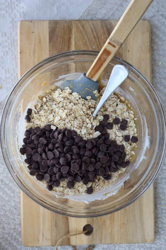 Folding rolled oats and chocolate chips into the dough.