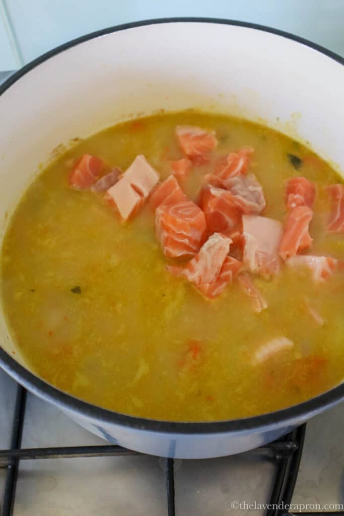 Adding the cubes of salmon into the soup base.
