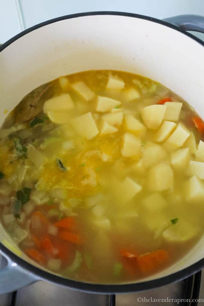 Cubed potatoes being added to the simmering pot.