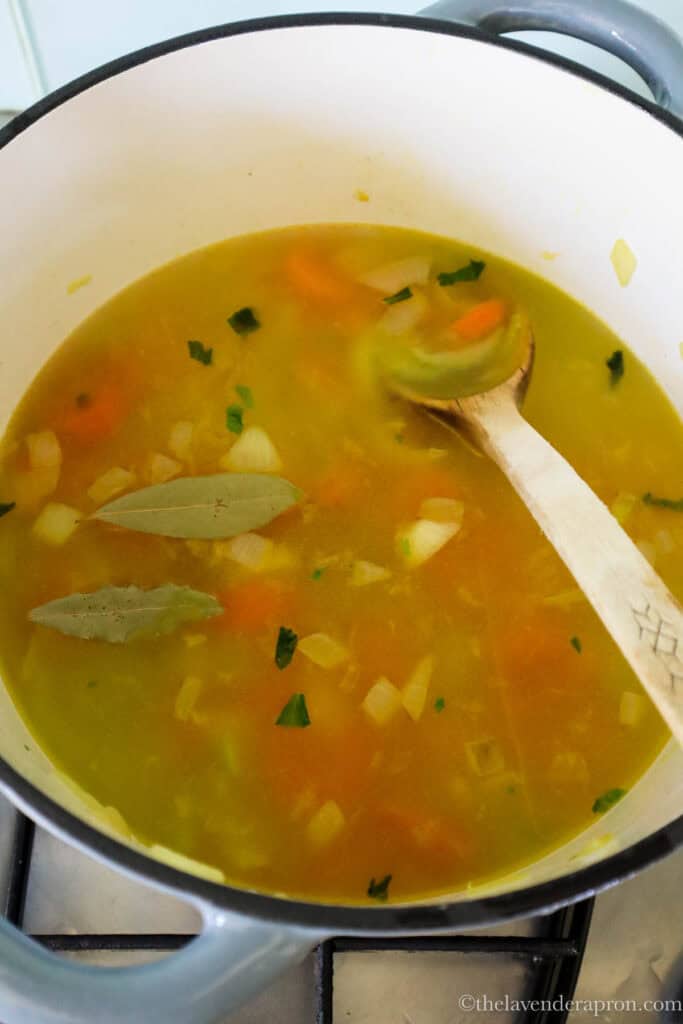 Water and bay leaves added to the softened vegetables in the pot.