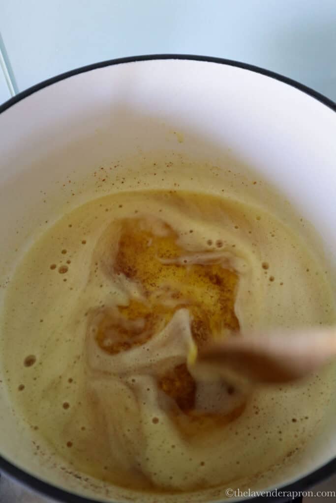Browning butter in a light colored pot showing brown flecks on bottom of pot.
