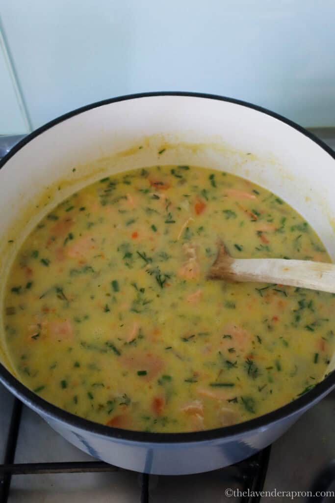 Stirring cream into the salmon soup off the heat.