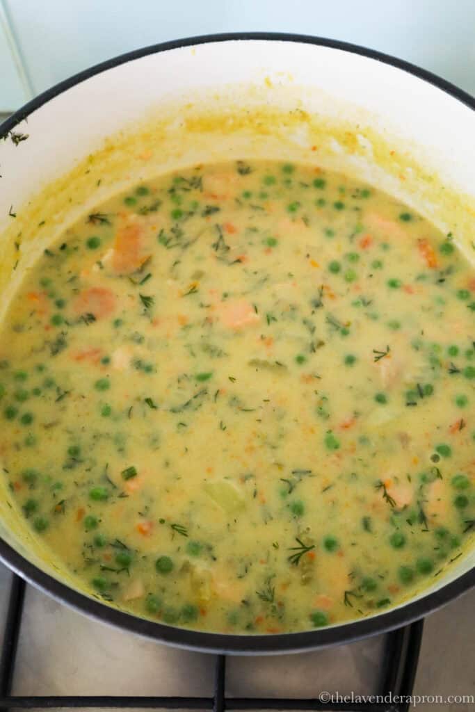 Creamy salmon soup with peas in pot.