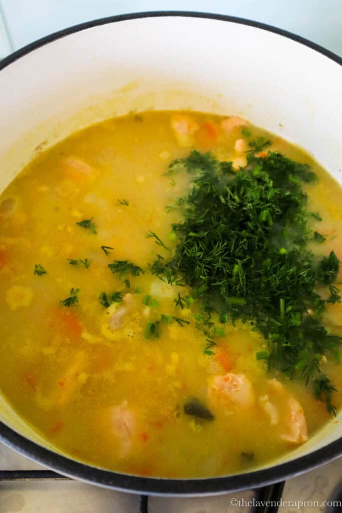 Adding finely chopped fresh dill to the salmon soup.