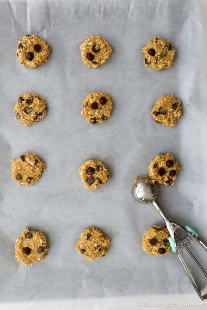 Using a cookie scoop to make even balls of dough on baking paper.