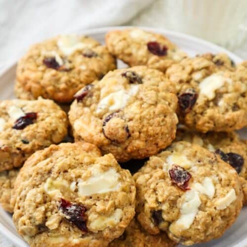 Oatmeal cranberry white chocolate cookies on a plate with a glass of milk.