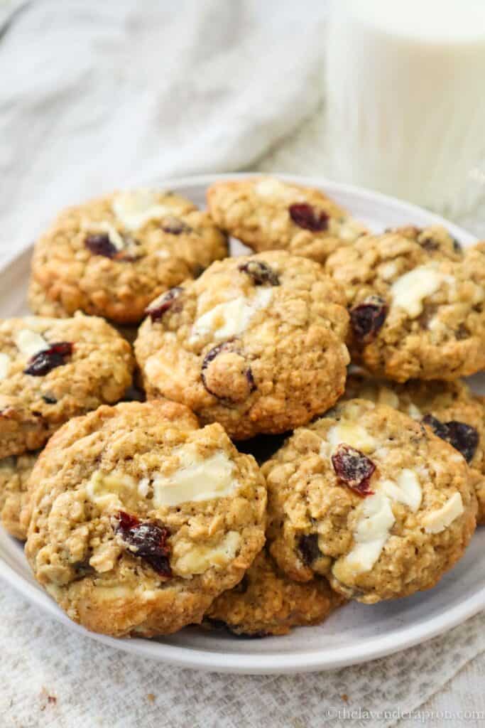 Oatmeal cranberry white chocolate cookies on a plate with a glass of milk.