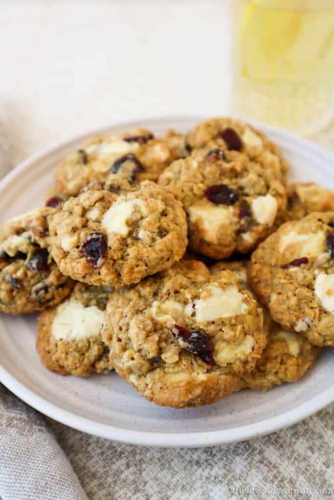 Oatmeal cranberry white chocolate cookies on a plate with a glass of chamomile lemonade.